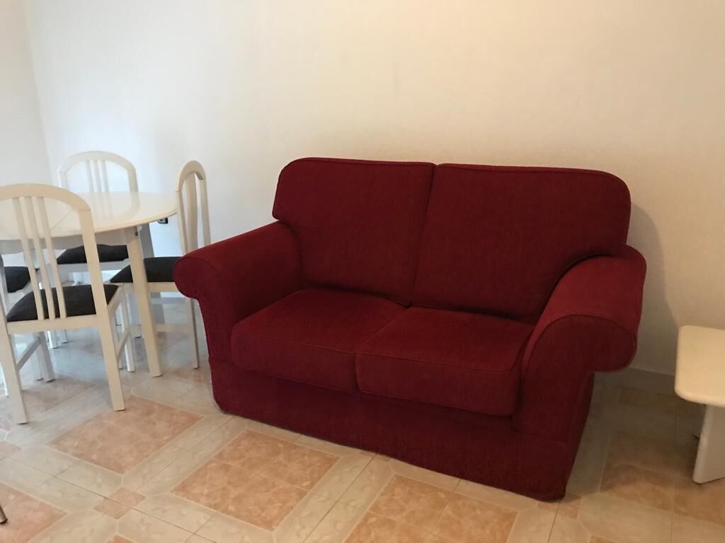Ein rotes Sofa in einem Raum mit weißen Stühlen und einem weißen Tisch.