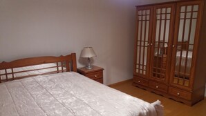 Ein Schlafzimmer mit einem Bett, einem Nachttisch mit Lampe und einem Holzschrank.