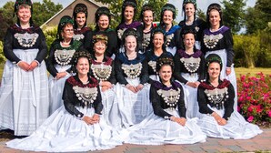 Un groupe de personnes, vêtues de costumes traditionnels, posent à l’extérieur.