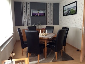A dining room with a wooden table, black chairs, and a patterned wallpaper.