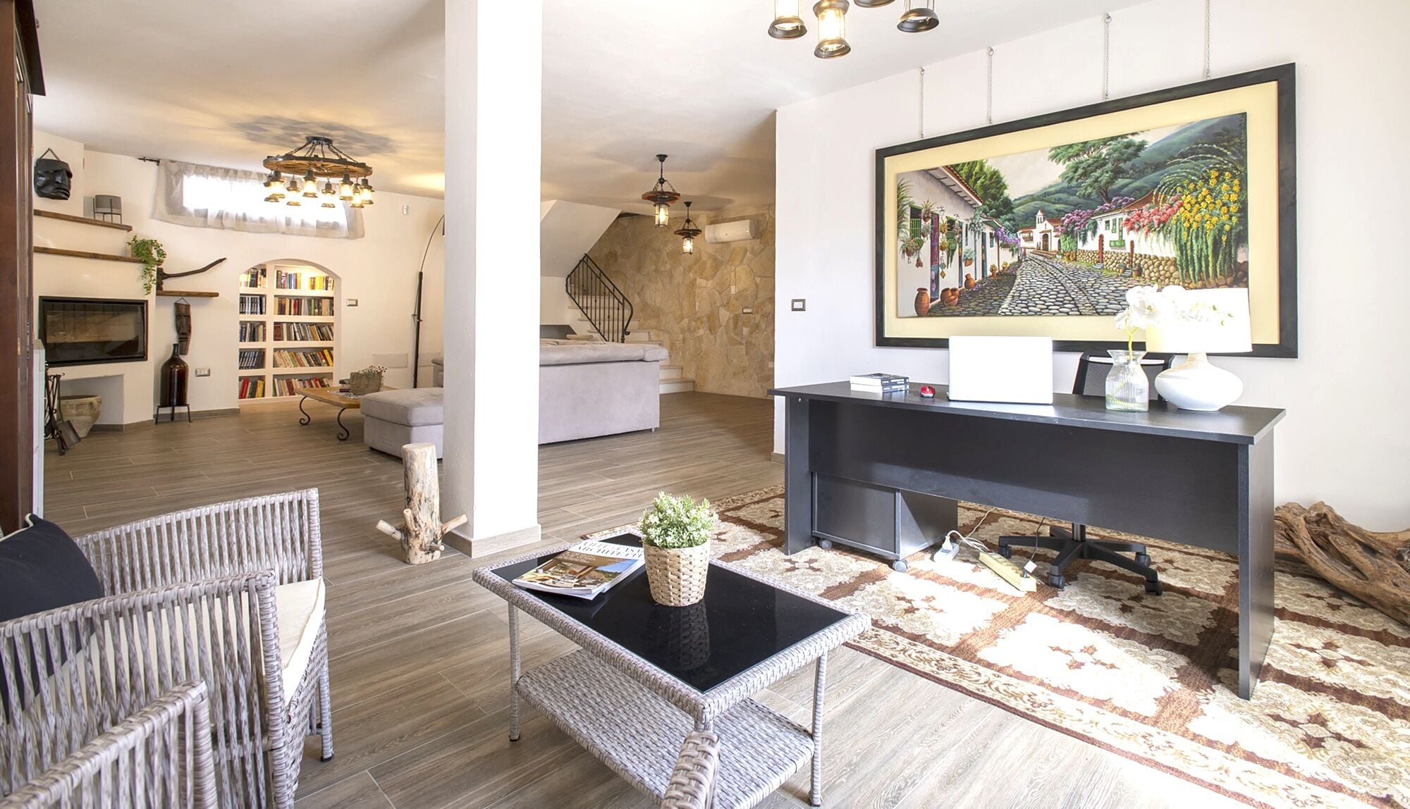 A modern living room with a fireplace, a large painting, and a cozy seating area.