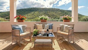 A balcony with wicker furniture, a glass table, and potted plants. - ClickSardegna Alghero Villa Flaminia, with independent swimming pool, SPA & Gym (Alghero)