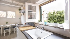 Eine moderne Küche mit einer weißen Spüle, einer Holzarbeitsplatte und einem Fenster mit Blick auf einen Garten.