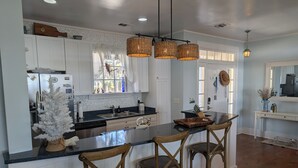 A modern kitchen with white cabinets, a black countertop, and a central island with bar stools.