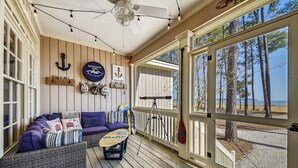 A covered porch with a wicker sofa, a small table, and a ceiling fan.