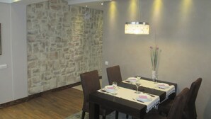 Un comedor con pared de piedra, una mesa dispuesta para cuatro personas y una lámpara colgante.