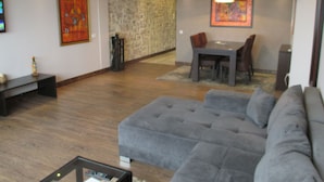 Una sala moderna con un sofá seccional gris, una mesa de comedor con sillas y una pared de acento de piedra.