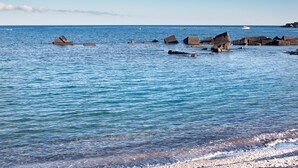 A coastal scene with clear blue water, scattered rocks, and boats. - SICILY ETNA SEA Beach&Pool Catania Taormina Etna District (Mascali)