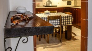 Una cocina con armarios de madera, una mesa de comedor con sillas y una lámpara colgante.