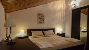 Una cama bien hecha con almohadas, una mesita de noche con lámpara, y un cuadro colgado en la pared.