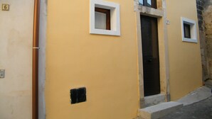 Un edificio amarillo con dos ventanas pequeñas y una puerta.
