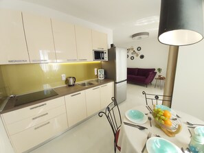 Et moderne køkken med mikroovn, køleskab og et spiseområde med et bord dækket til to.
