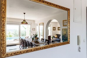 A dining area with a large mirror, a chandelier, and a view of an outdoor patio.