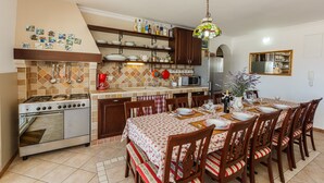 A kitchen with a stove, microwave, and dining table set for six. -  Idyllic Villa near Split, pool, garden, free parking and stunning view, (OWNER) (Solin)