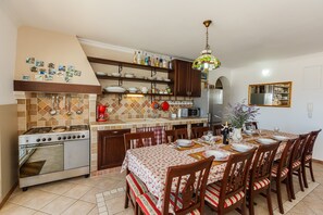 A kitchen with a stove, microwave, and dining table set for six. -  Idyllic Villa near Split, pool, garden, free parking and stunning view, (OWNER) (Solin)
