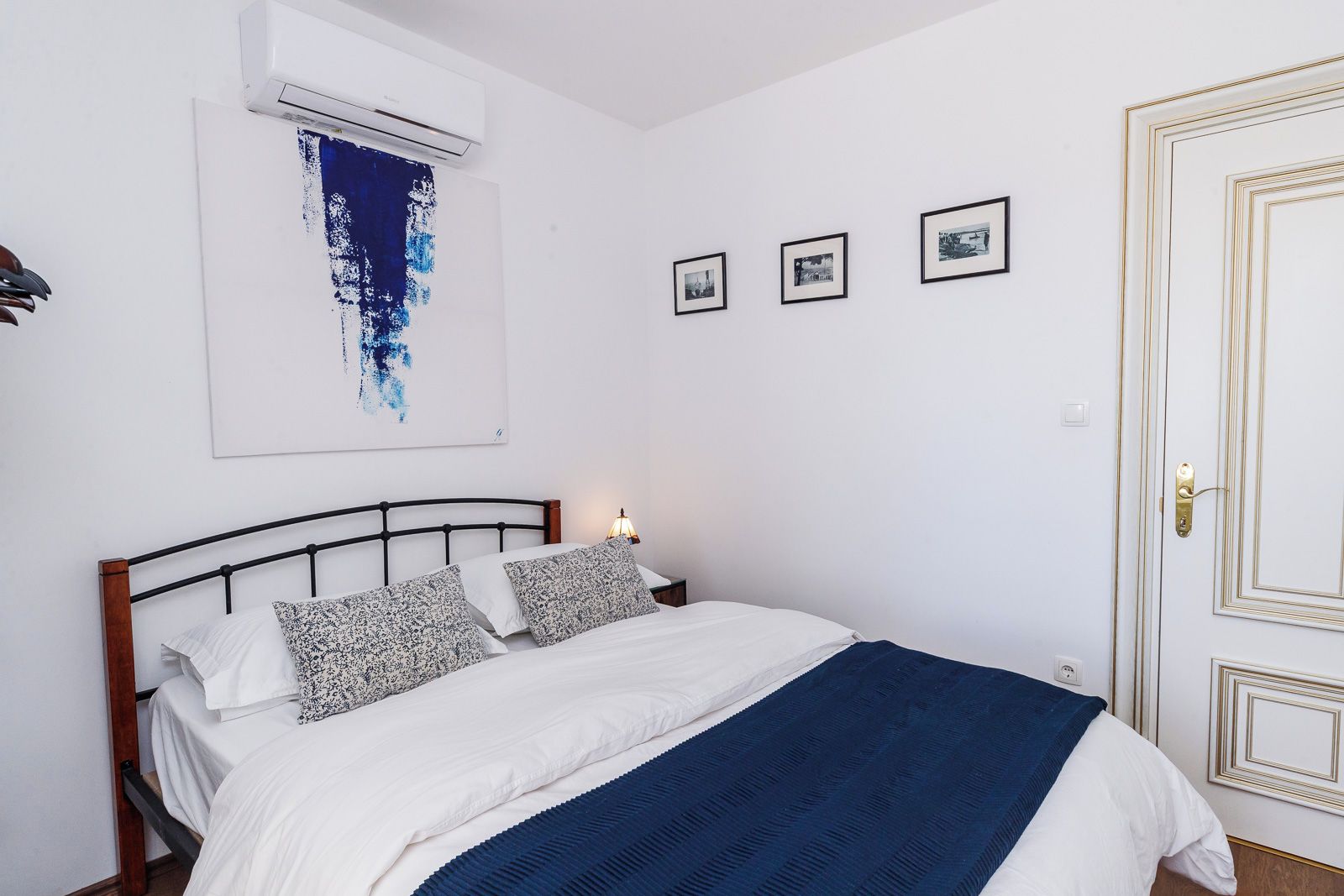 Una camera da letto con un letto, un condizionatore d'aria a muro e quadri appesi alle pareti.