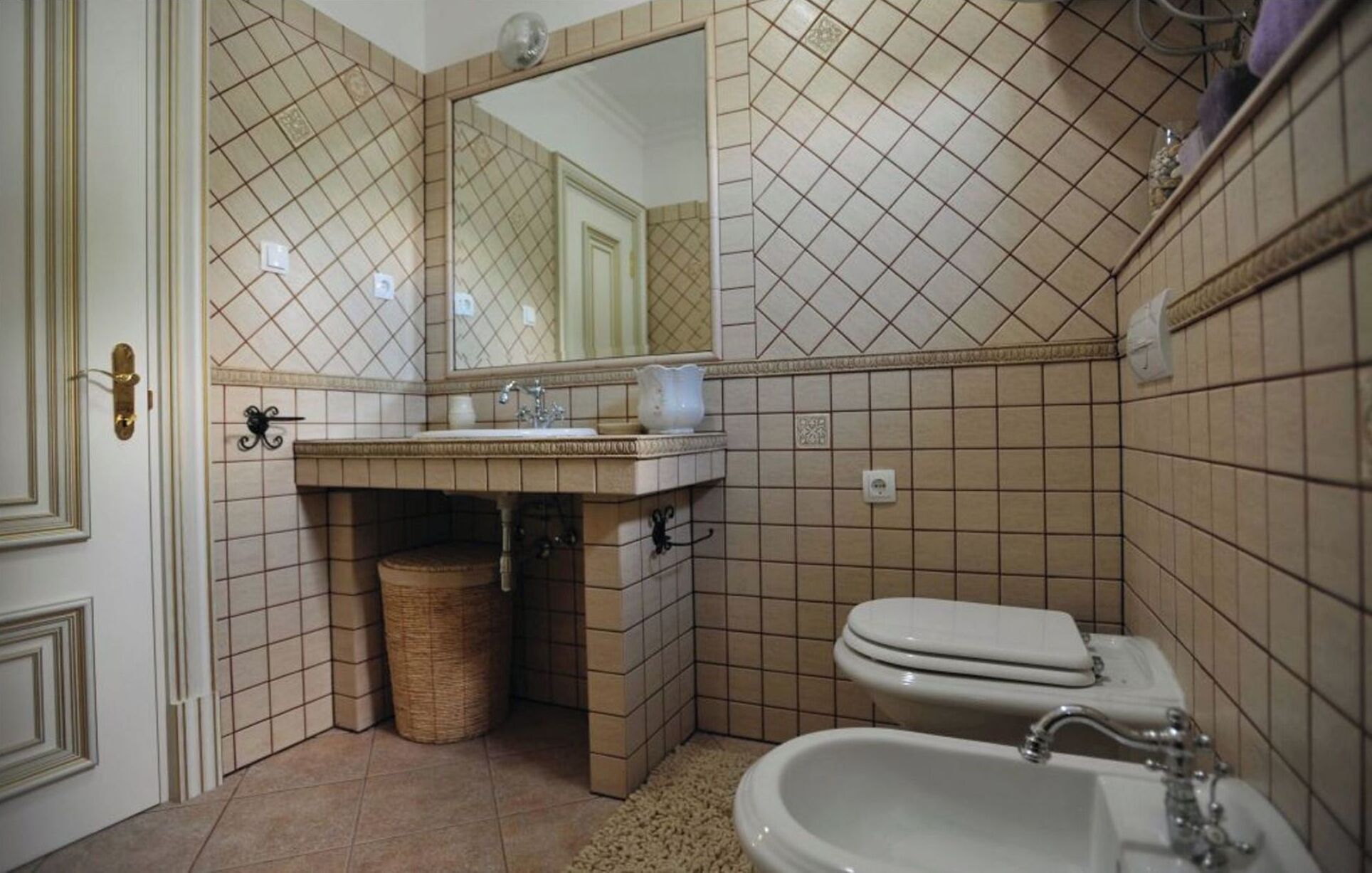 Un bagno con lavandino, specchio, water e bidet.