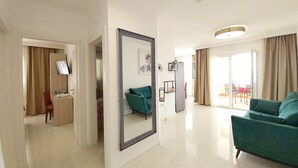 A modern living room with a green sofa, a large mirror, and a flat-screen TV mounted on the wall.