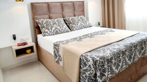 A modern bedroom with a tufted headboard, patterned bedding, and pendant lights.