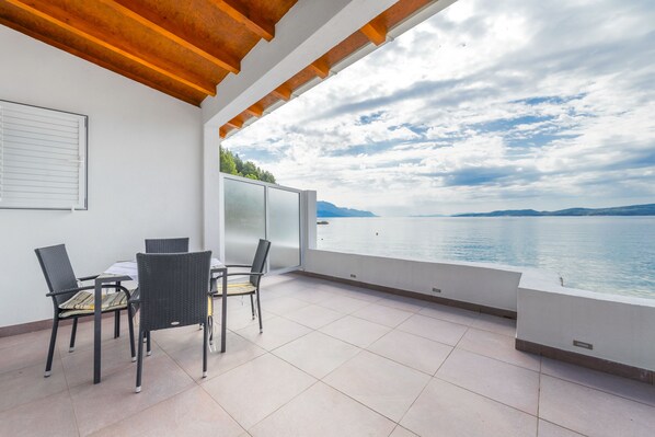 Un balcon avec une table et des chaises, une vue sur la mer et un plafond en bois.