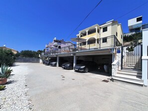 A residential street with a row of parked cars, a gated entrance, and a building with a balcony. - Family apartment with sea view and Heated swimming pool a9 (Okrug Gornji)