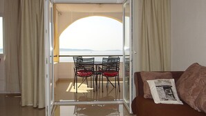 Quarto com porta de vidro que dá para uma varanda com mesa e cadeiras.