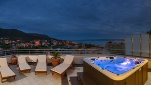 A rooftop terrace with lounge chairs, a hot tub, and a view of a coastal town at dusk. - EXCLUSIVE VILLA ARYA private heated pool, gym, sauna, roof hot tub near the sea. (Podstrana)