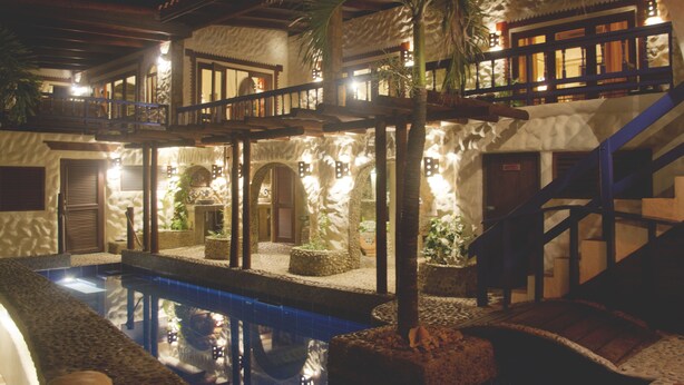 A pool area with a stone wall, palm trees, and a wooden staircase. - Villa Beachcliff,  "The Perfect Island Sanctuary" (Lance Aux Epines)