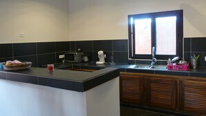 A kitchen with a black countertop, a microwave, a coffee maker, and a window with blinds. - Charming recent air-conditioned 3 bedroom villa with swimming pool  (Ngaparou)