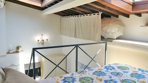 A bedroom with a bed, a window with a curtain, a ceiling fan, and a small table with a plant. - Santa Croce Studio in the historic center (Firenze)