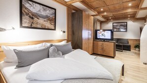 A modern hotel room with a wooden ceiling, a bed with white and grey bedding, a TV, and a framed landscape picture on the wall. - Apart amber with 135 m² with a large sunny terrace for 6-11 people (Ried im Oberinntal)
