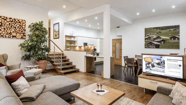 A modern hotel lobby with a sofa, coffee table, and a TV displaying local attractions. - Apart amber with 135 m² with a large sunny terrace for 6-11 people (Ried im Oberinntal)