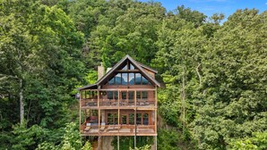A wooden cabin with a balcony and large windows, surrounded by dense forest. - EndlessViewSleeps15.Amazing Viewover  Dollywood&ParrotMtn.Close to Pkwy,private (Sevierville)