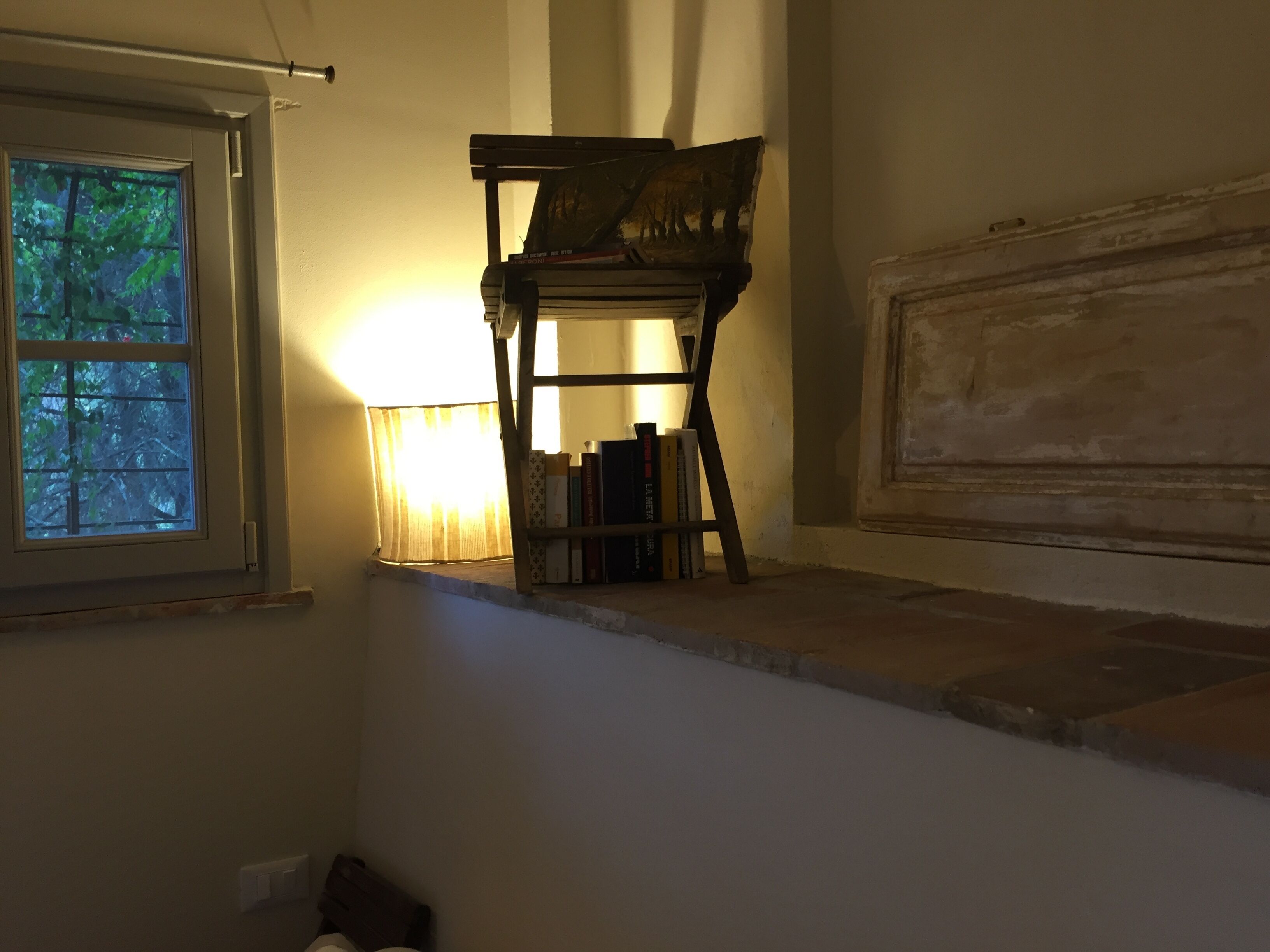 A room with a window, a bookshelf, and a lamp.