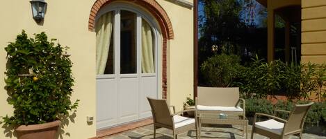 A patio with stone flooring, a potted plant, wicker furniture, and a white door with a window.