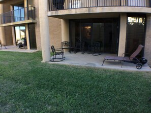 A building with a covered outdoor seating area, including chairs and a lounge chair. - 100 Steps to the beach! Condo 3bedroom 2 bath Sleeps 8 Ocean views (south padre island)