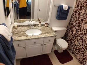 Un bagno con lavabo in granito, mobili bianchi, un water e carta da parati decorata.