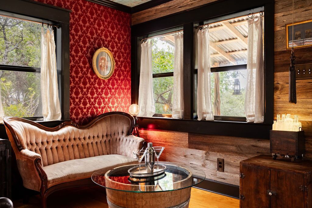 Una habitación con un sofá capitonado, una mesa de centro de vidrio y un mueble de madera.