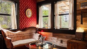 Una habitación con un sofá capitonado, una mesa de centro de vidrio y un mueble de madera.