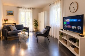Una sala de estar moderna con sofá, sillón, mesa de centro y un televisor de pantalla plana mostrando servicios de streaming.