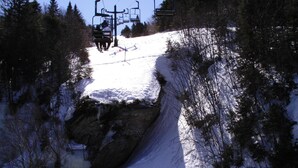A snow-covered ski slope with a ski lift and trees.