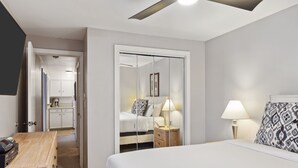 A hotel room with a bed, bedside table, lamp, and a wardrobe with a mirror. - Outpost: Tensleep B6 (Teton Village)