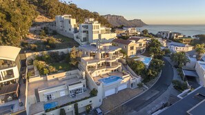Zona residencial costeira com casas modernas de vários andares, piscina e vista para o mar.