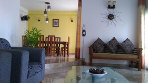 A living room with a sofa, chairs, a glass coffee table, and a dining area with a table and chairs. - Villa With Private Plunge pool (Panadura)