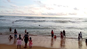 A beach scene with people engaging in various activities like swimming and walking along the shore. - Villa With Private Plunge pool (Panadura)