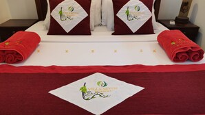 A neatly made bed with red towels, pillows, and a blanket featuring the logo of Villa Seven Panadura. - Villa With Private Plunge pool (Panadura)