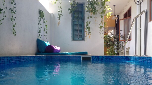 A swimming pool with a blue tiled edge, a small window with blue shutters, and a metal ladder on the right. - Villa With Private Plunge pool (Panadura)