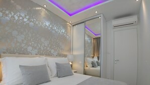 A modern bedroom with a large bed, a mirror, and an air conditioning unit.