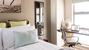 Une chambre d’hôtel avec un lit, un bureau avec un ordinateur portable, une chaise et une grande fenêtre.