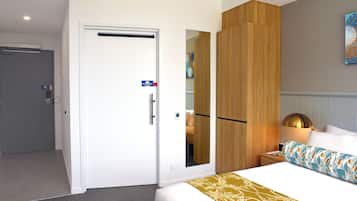 Een hotelkamer met een bed, nachtkastje, spiegel en kledingkast.